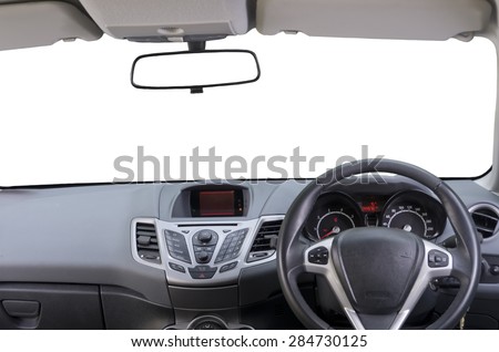 Interior of right hand drive car. Image shows driver controls, dashboard, central rear view mirror and sun visors. Windscreen (windshield) is isolated white, so as rear view mirror.