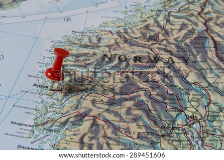 Bergen marked with red pushpin on map. Selected focus on Bergen and bright red pushpin. Pushpin is in an angle. Some parts of Norway can be seen on map.