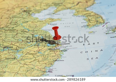 Shanghai marked on map with red pushpin. Selective focus on the word Shanghai and the pushpin. Pin is in an angle and casts some shadow to the left.