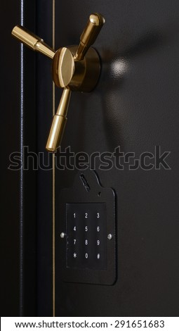 Black gun safe door with numbered dial pad for pin and golden door handle.