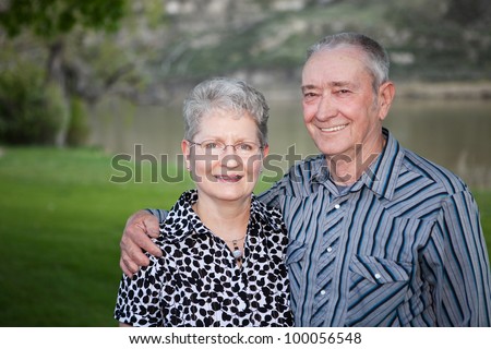 A lovely portrait of  a happy Canadian senior couple outdoors.  Man is missing ends of two fingers.
