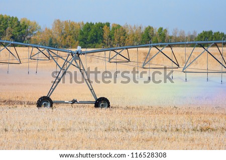 A rainbow of colors are reflected in the water droplets coming from an agricultural watering system pivot.