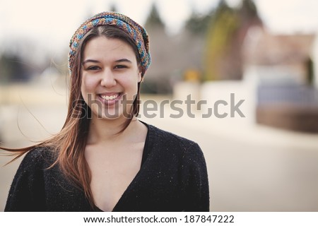 Portrait of a twenty-four year old woman on the street wearing a slouch hat she crocheted for herself. Casually dressed with no makeup.