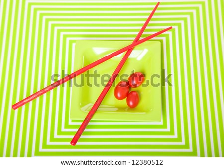 Eye-popping tomato & chopstick still life on geometric patterned mat.