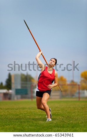 A young, female athlete throwing a javelin in a track and field event.