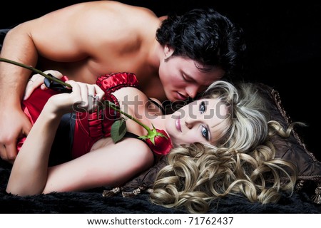 Romantic couple in lingerie with red rose on black background.