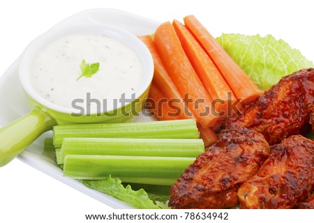 Hot wings served on a bed of lettuce, with fresh carrot and celery sticks.  A cool ranch dip for the vegetables, compliments the hot flavor of the wings.  Shot on white background.