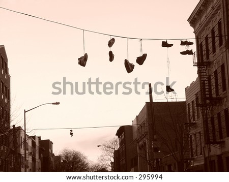 sneakers on a phone line stung across the street with buildings and trees in the background