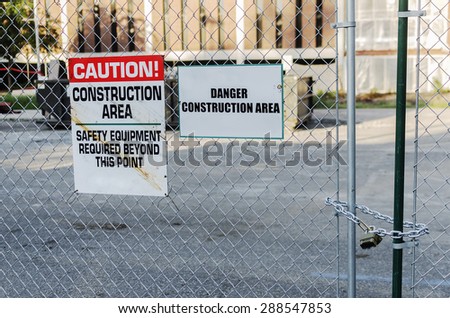 Construction Site With Locked Gate And Caution Sign.\
\
Warning sign making people aware of dangers around a construction area.