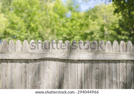 Wooden Fence With Copy Space Above During Summer. Top of a wooden old, classical fence with copy space above with trees and sky in background.