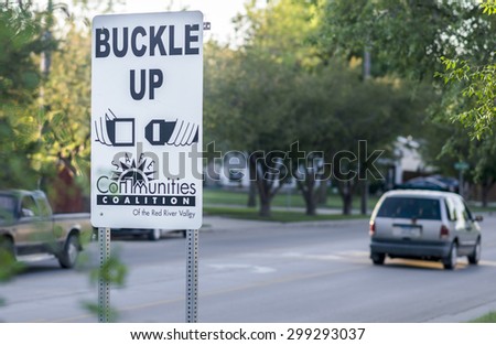 Moorhead, Minnesota, United States - July 21, 2015: Buckle up road sign by a suburban neighborhood, promoted by the local community.