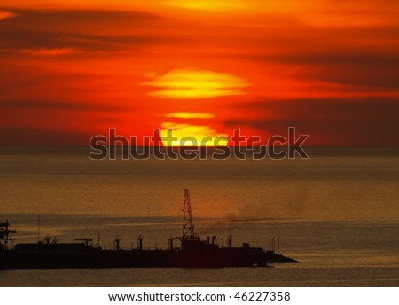 Big round sunset hiding behind the clouds over the horizon on Gulf of Mexico (from Mexico Campache) with silhouette of a big ship