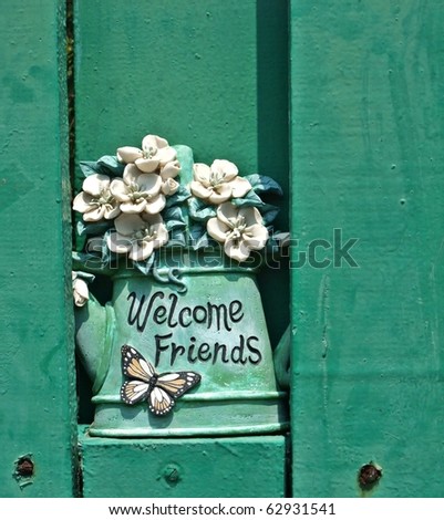 Clay art flower pot with welcome friends greeting on green wall wooden background - background resources