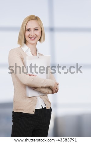 young businesswoman holding folder, standing in office