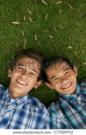 Happy brothers laying on the grass.