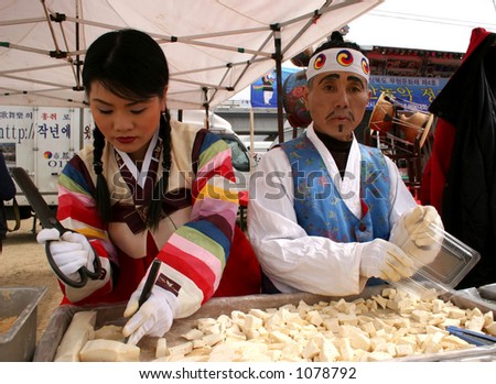 Korean man and woman in traditional clothing cut candy at a festival in South Korea