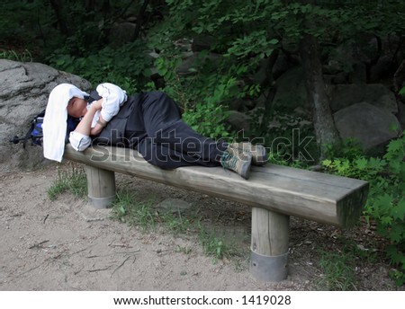 Hiker takes a nap on a bench after climbing a mountain