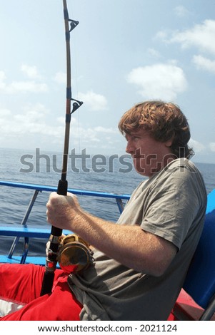 Man deep sea fishing. Pulling on the rod to catch a fish.