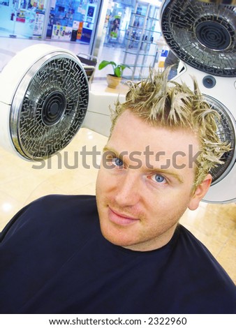 Attractive young man having his hair colored blond at the hairdressers.