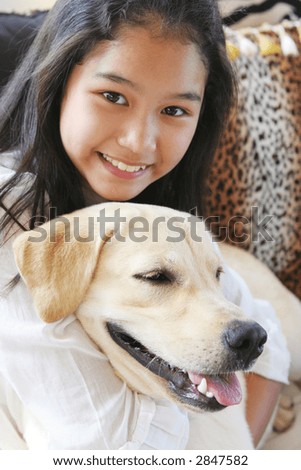 Smiling Asian girl on animal print sofa with her pet dog