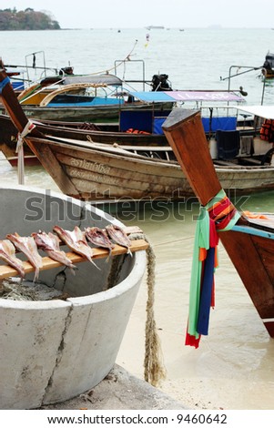 Fish out to dry with fishing boats in the background, Phi Phi Island, Thailand - travel and tourism.