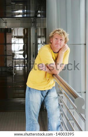 Portrait of a man leaning on the railing of an modern building.