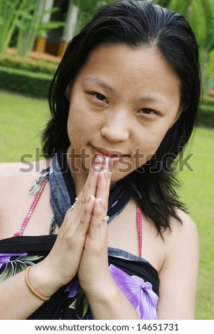 Asian woman giving a traditional Thai greeting (wai).
