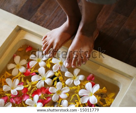 Indian woman (with henna) about to soak her feet in water decorated with flowers.