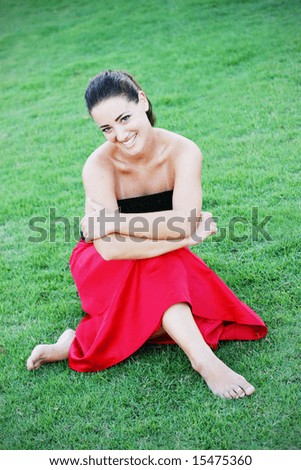 Beautiful young woman sitting outside on the grass.