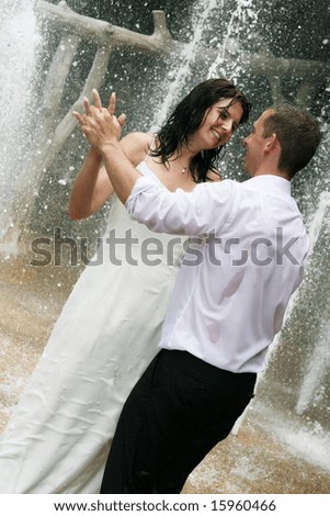 Romantic bride and groom dancing under a water fountain - trash the dress trend.