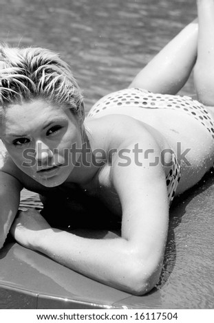 Beautiful young woman wearing a bikini by the swimming pool.