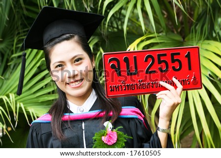 Beautiful young Asian graduate in robes on graduation day. Number plate says \