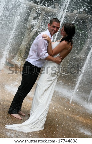 Bride and groom celebrating their wedding day with a dance under a water fountain.