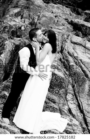 Happy bride and groom kissing on top of a mountain.