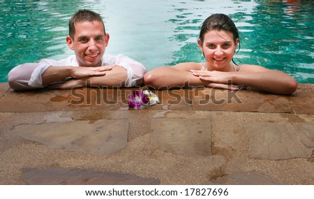 Happy bride and groom in the swimming pool during a trash the dress photo shoot.