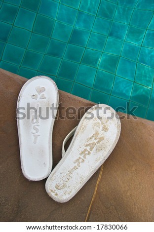 Just married flip flops at the side of a swimming pool.