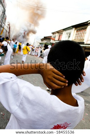 PHUKET - OCTOBER 3: A boy covers his ears during fireworks at the Vegetarian Festival October 3, 2008 in Phuket, Thailand.