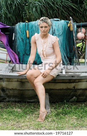 Portrait of a blond woman sitting on an old  boat.