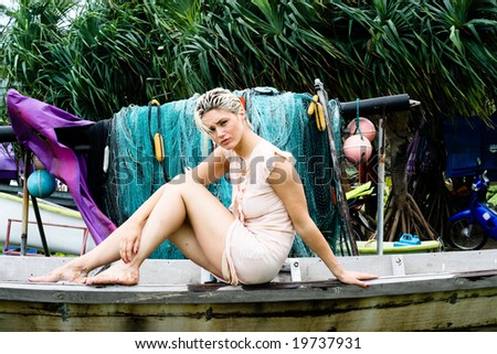 Beautiful blond woman sitting on a fishing boat.