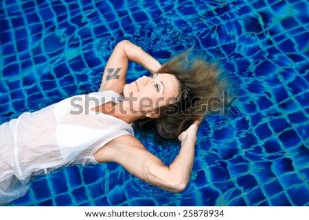 Beautiful blond woman in the swimming pool - trash the dress trend.