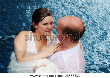 Gorgeous bride and groom playing in the water during a trash the dress photo shoot.