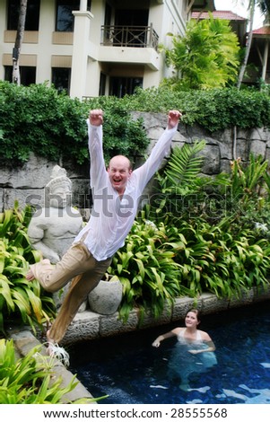 Groom jumps into the water during a trash the dress photo shoot.