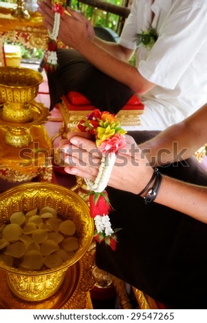 Close-up of a Western couple getting married during a traditional Buddhist wedding in Thailand.