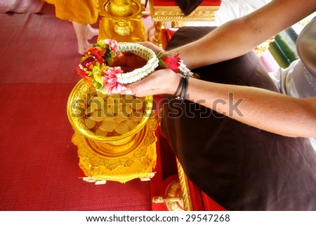 Close-up of a Western couple getting married during a traditional Buddhist wedding in Thailand.