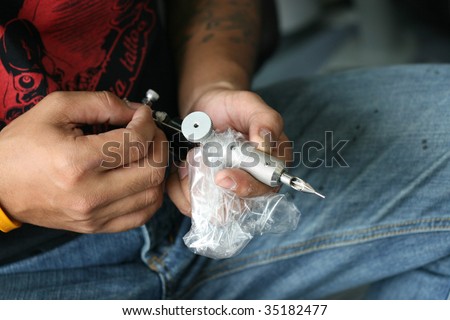 Close-up of a tattoo artist holding a needle gun.