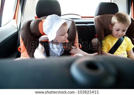 Little brother and his baby sister traveling in baby car seats