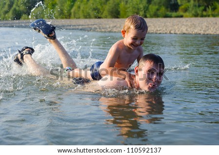Young father and his little son swimming in river