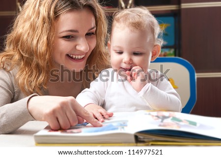 Young mother with her little daughter reading book