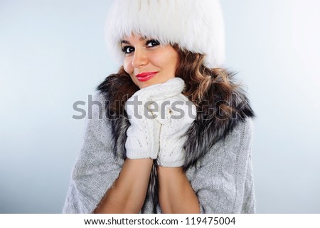 Beautiful young woman in white knitted gloves and fur hat