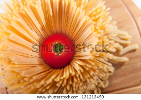 Fresh red tomato inside spaghetti pasta. View from above
